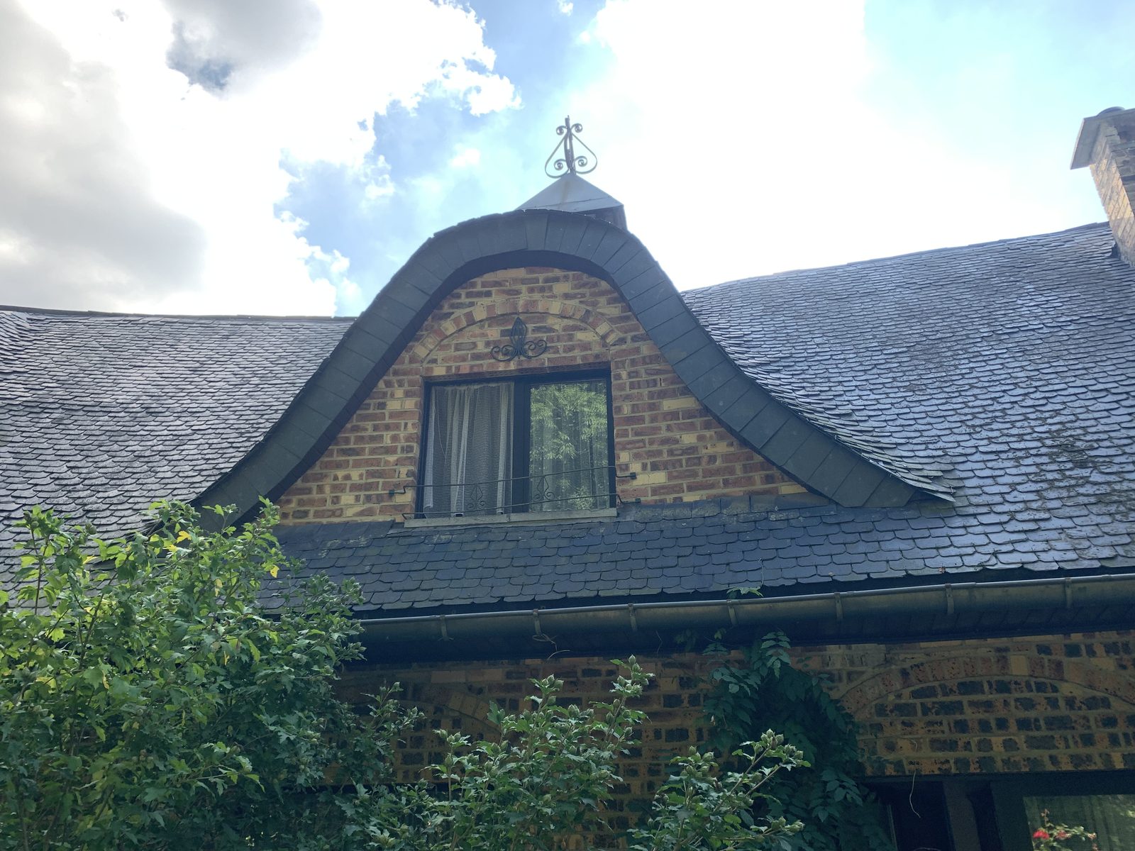 Dormer cintré patrimonial avec ses ardoises restaurées et son épi en fer ouvragé