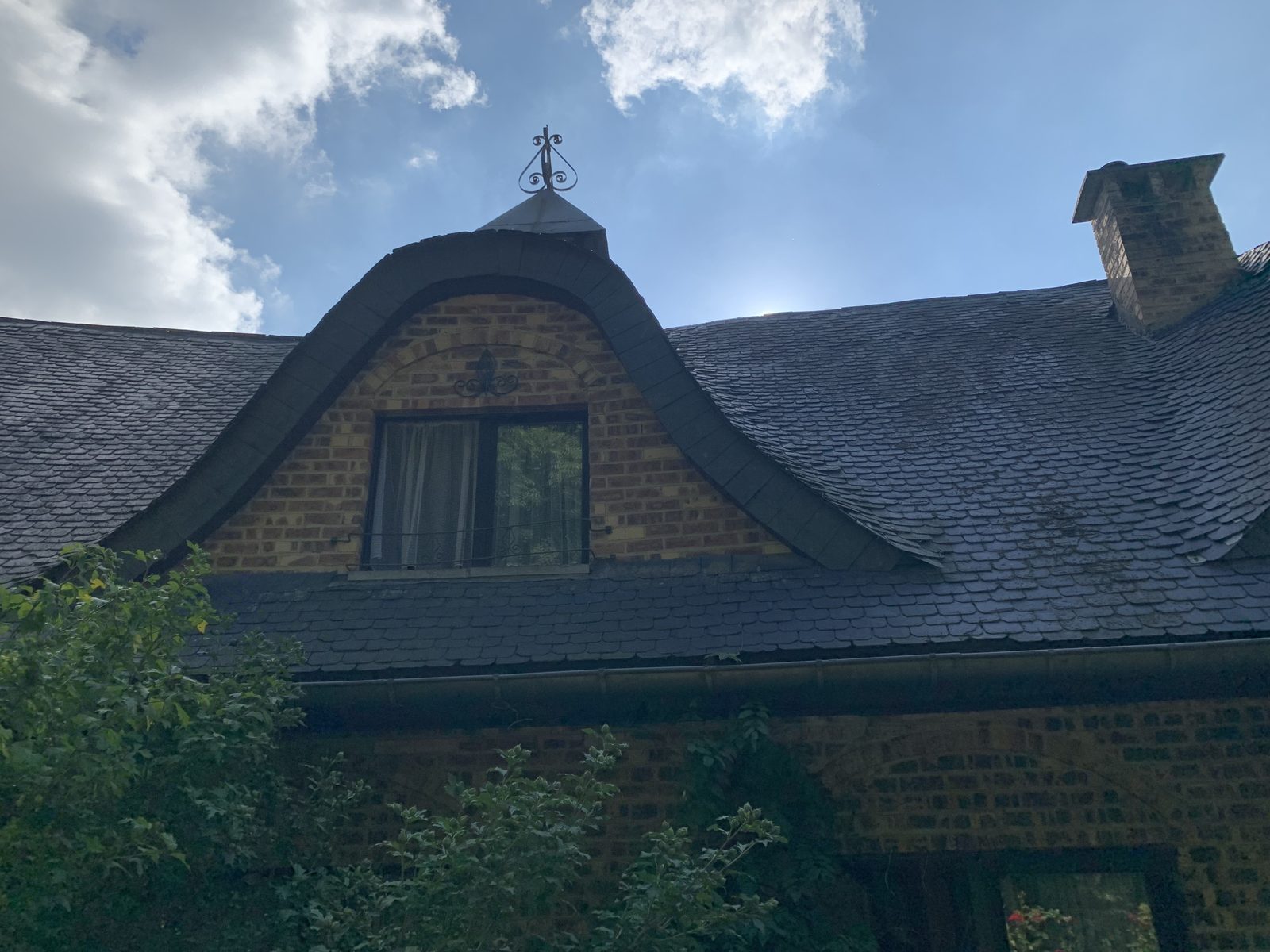 Vue extérieure de la toiture ardoise restaurée avec dormer et cheminée